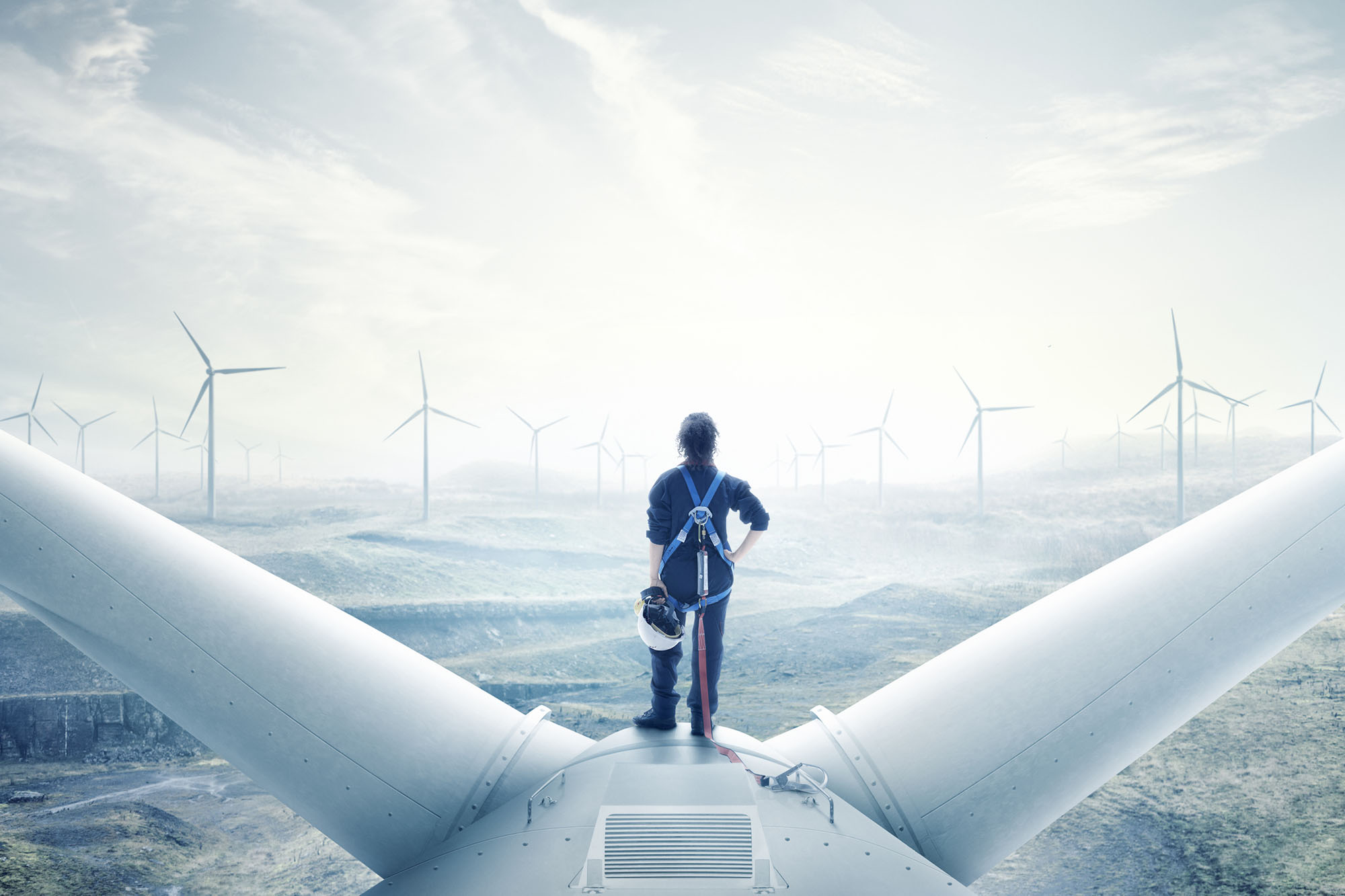 Female engineer standing on top of a wind turbine