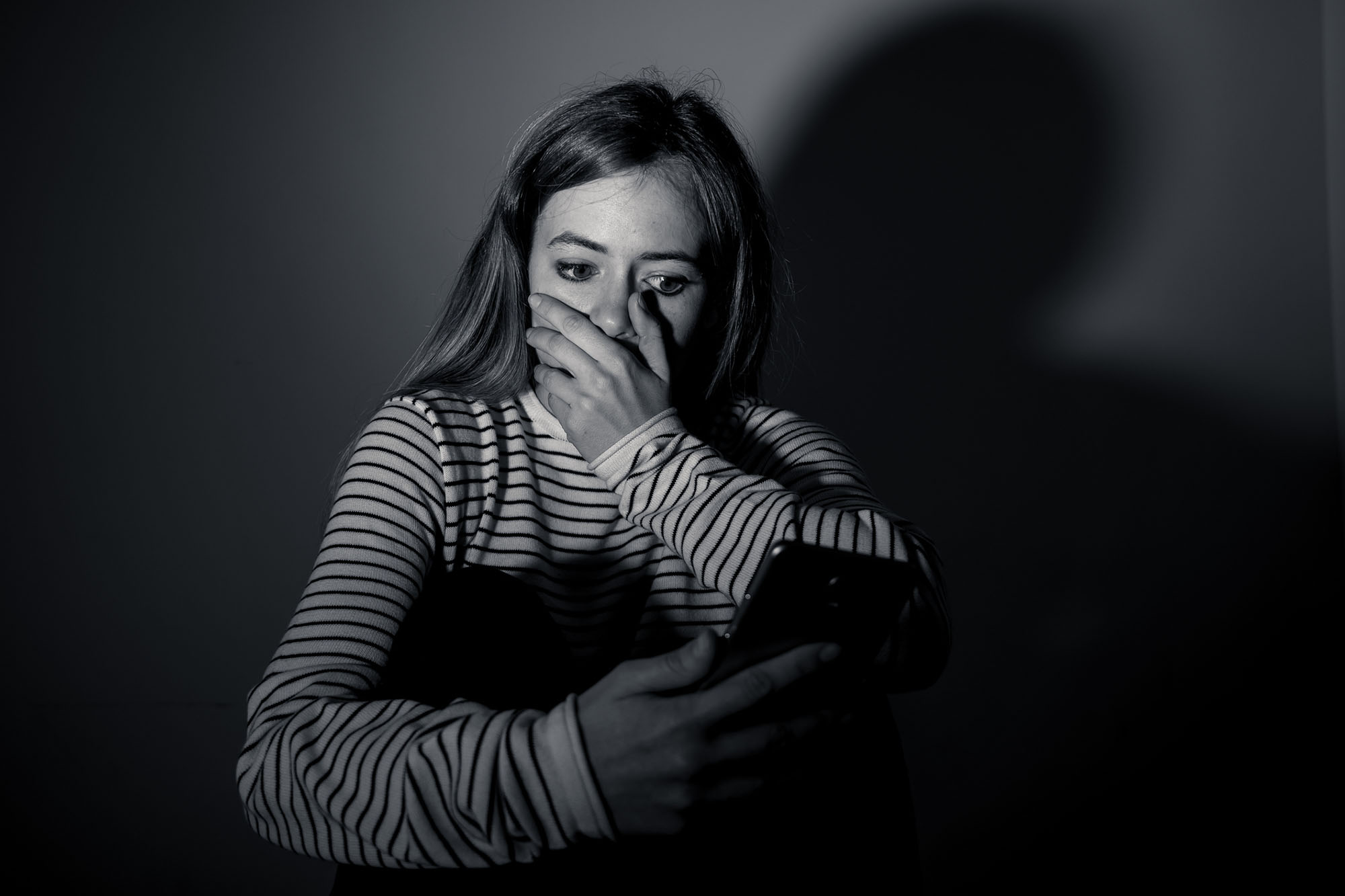 Sad desperate young teenager female girl on smart phone suffering from online bulling and harassment 