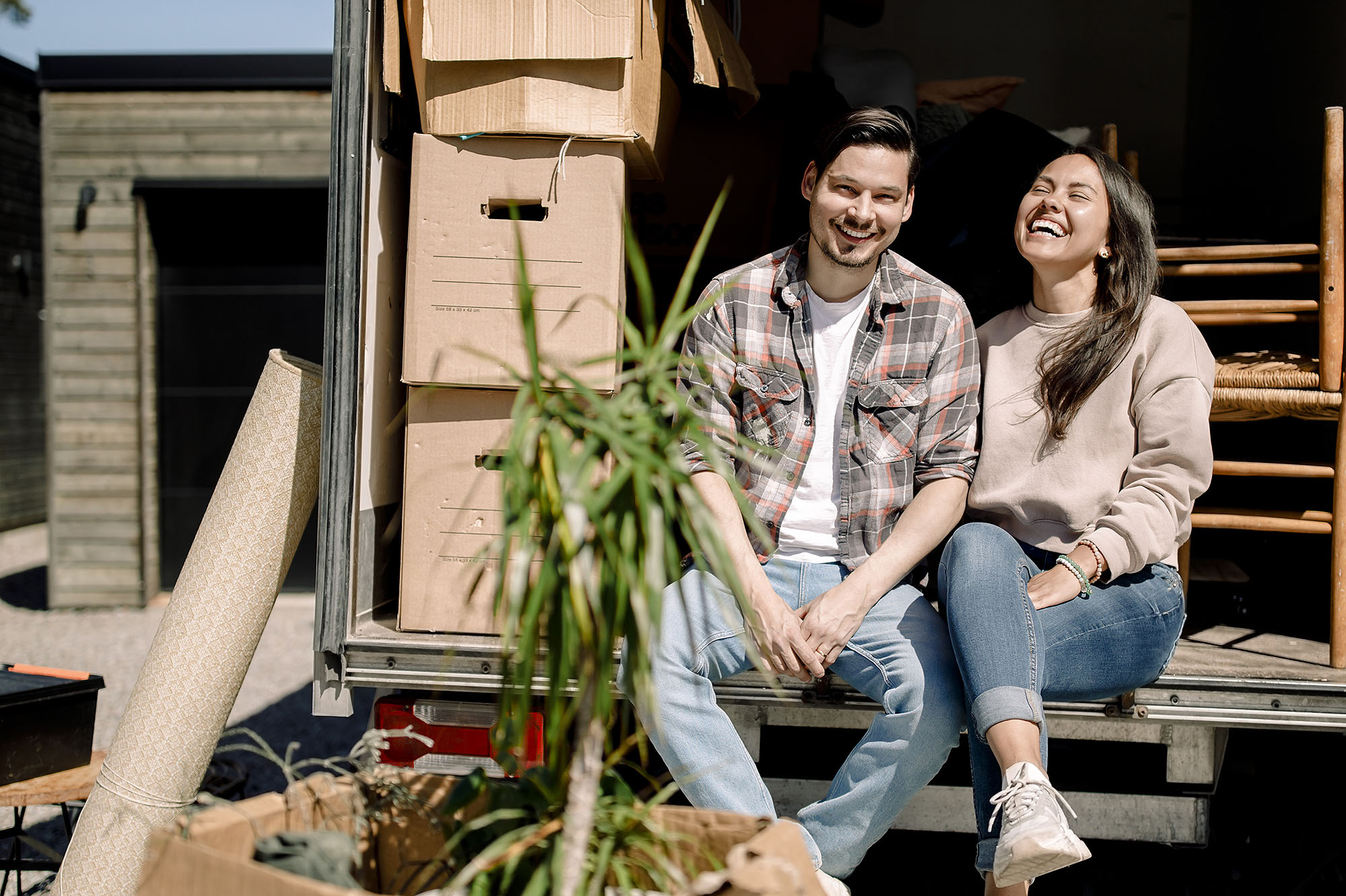 Portrait of happy couple sitting in delivery truck during sunny day