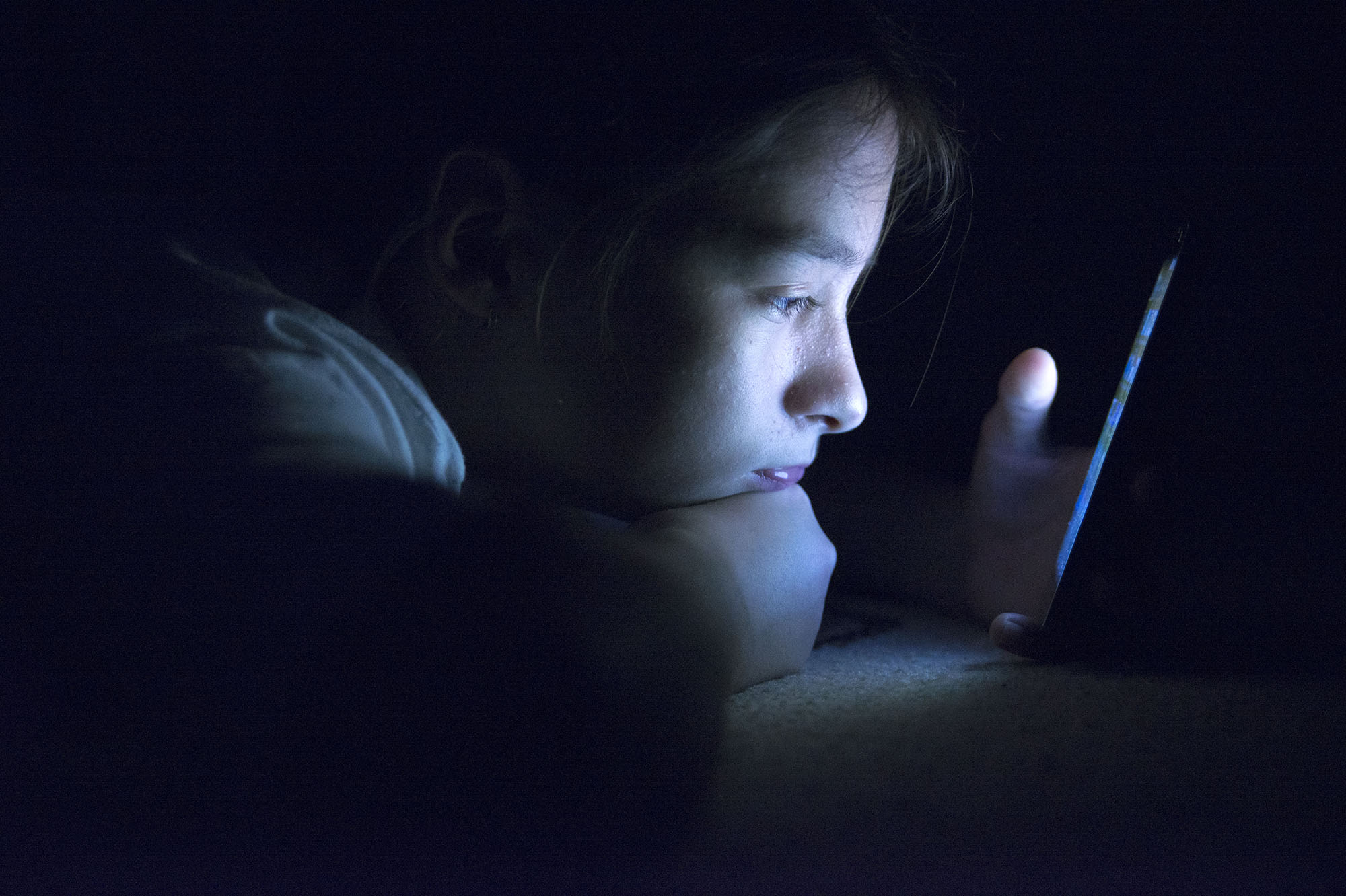 Teenager sending email from smart phone in her bed