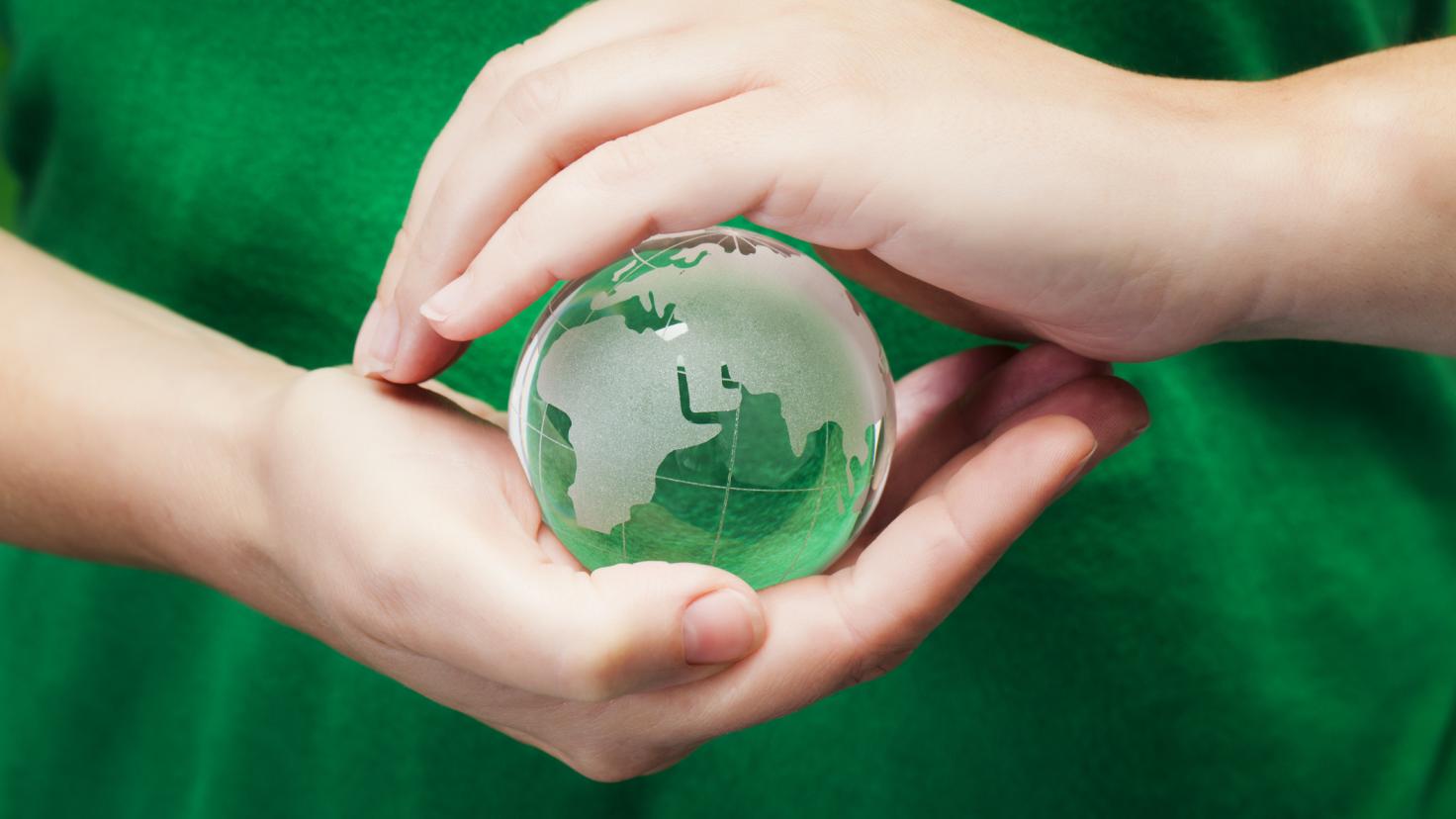 Una persona sostiene un globo de cristal delante de su camiseta verde