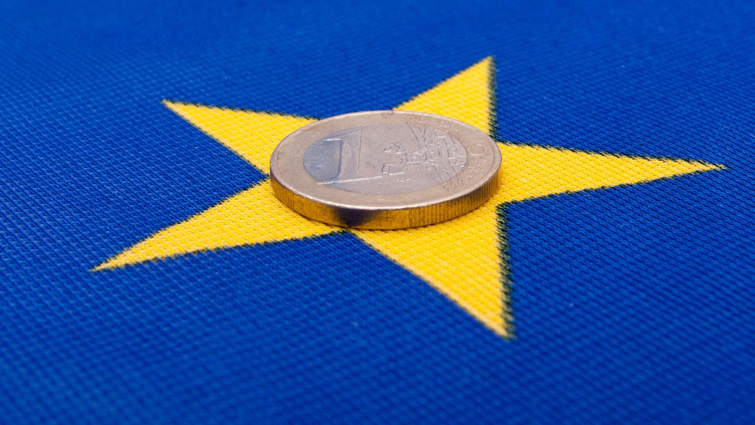 A Euro coin sits on a yellow star of the European flag