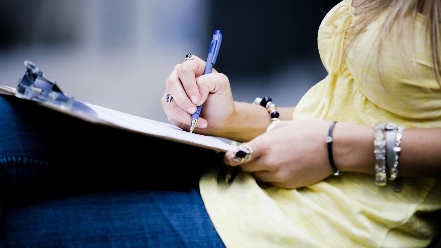 Uma mulher assina um documento em uma prancheta