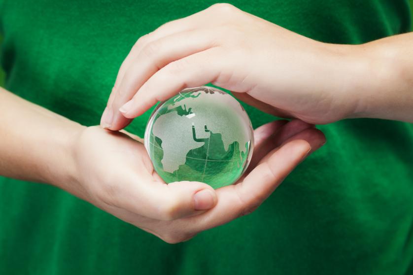 Oseba pred zeleno majico drži stekleni globus