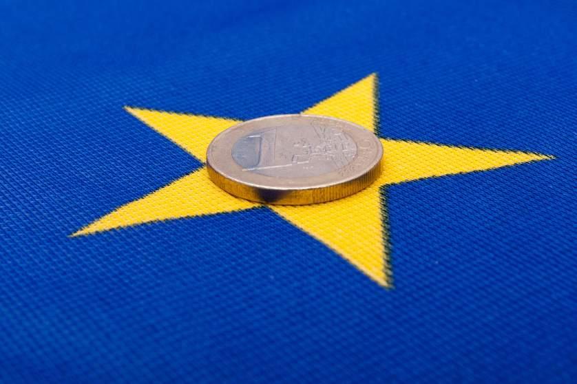 A Euro coin sits on a yellow star of the European flag
