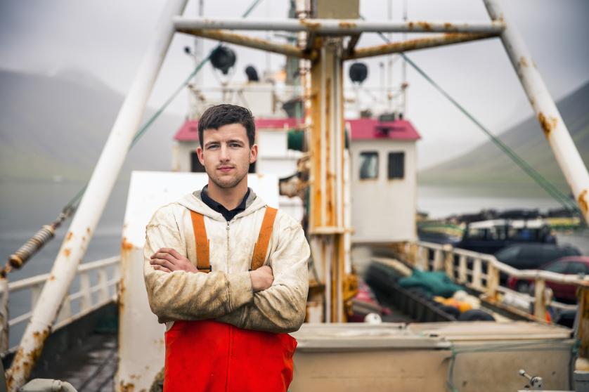 A man in fishing gear stands on his trawler
