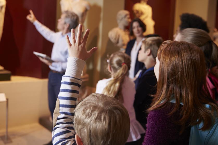 Deček, ki stoji s sošolci, dvigne roko