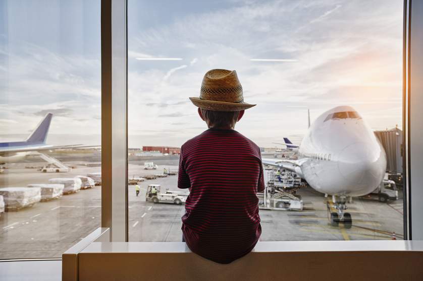 Boy sitting at the airport watching the planes 