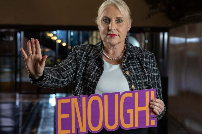 MEP Angelika Winzig showing a sign that says "enough" to violence against women