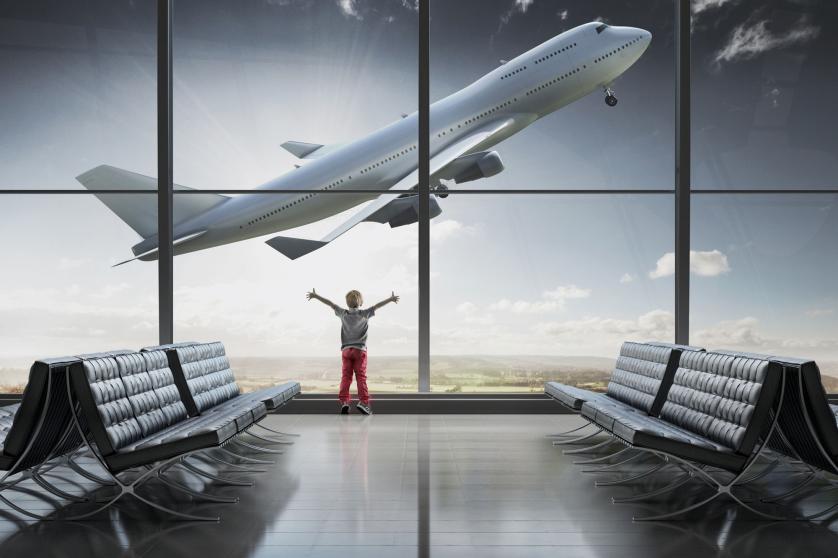 Boy looking at airplane taking off in airport term