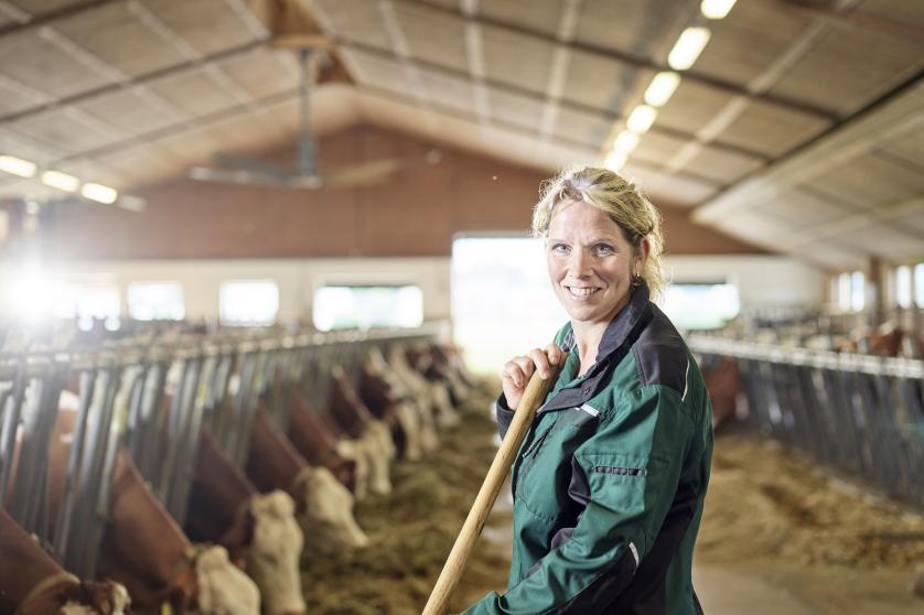Muotokuva hymyilevästä naispuolisesta maanviljelijästä maatilan tallissa