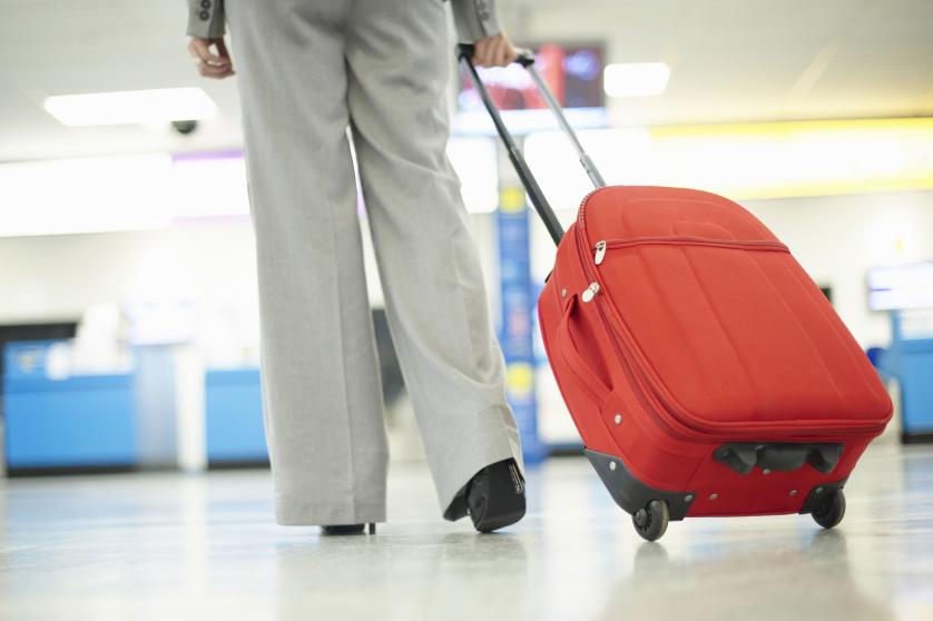 Young business woman walking with luggage towards check in gates in airport