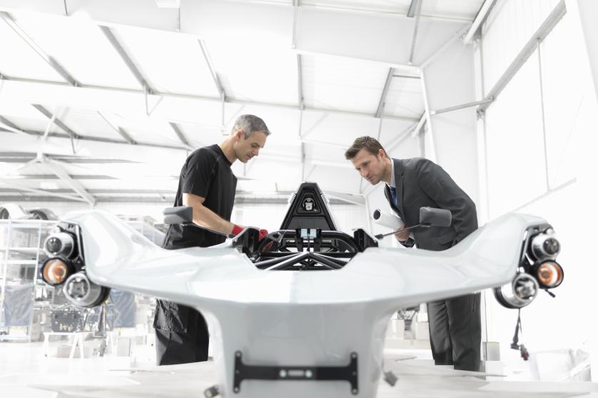 Inžinierius ir automobilių dizaineris automobilių gamykloje apžiūri iš dalies pagamintą superautomobilį