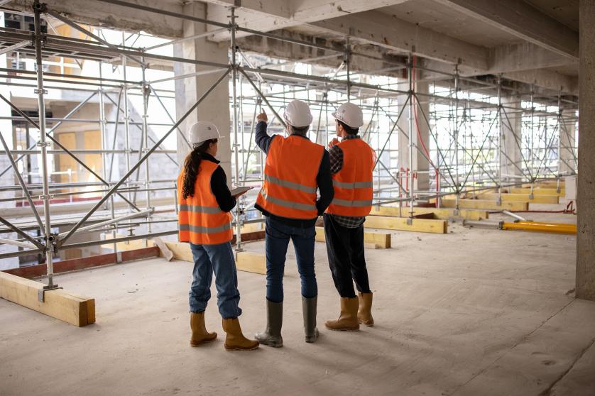 Trois travailleurs (architectes, ingénieurs) examinant un chantier de construction