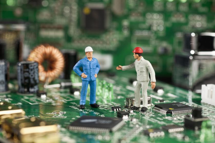 Deux figurines miniatures travaillant sur une carte mère d