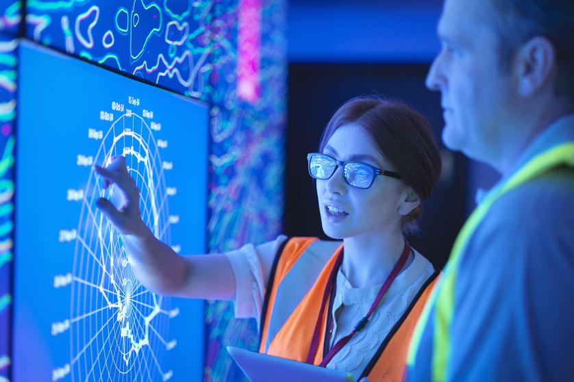 Femme géologue avec un collègue étudiant la représentation graphique de roches pétrolifères et gazéifères sur des écrans.