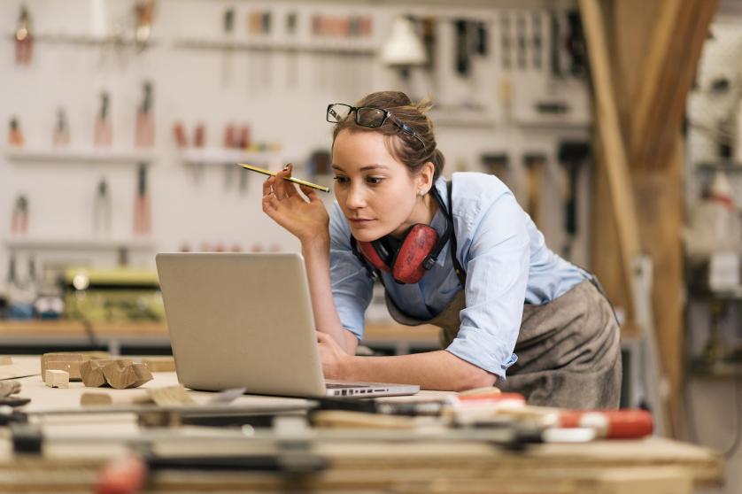 young carpenter in wood workshop using labtop