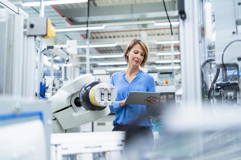 Businesswoman with tablet at assembly robot in a factory