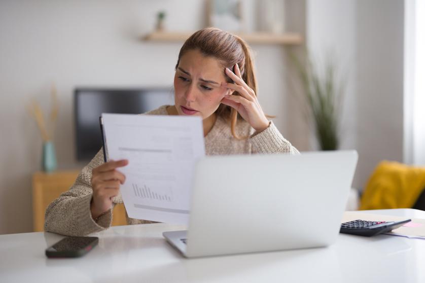 Fiatal nő aggódik a háztartási számlák miatt, ellenőrzi a pénzügyeit, és problémái vannak azok kifizetésével