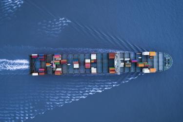 A large container ship is approching the port full loaded with containers and cargo