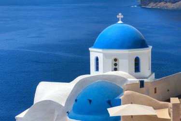 The iconic blue domed churches of Oia, Santorini, Greece, which contrast beautifully with the white buildings and blue sea