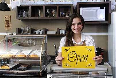 Young female entrepreneur showing open sign 