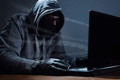 Hooded hacker steeling data from a laptop