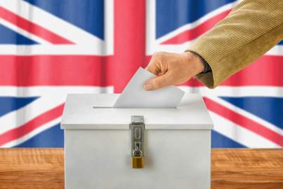Wahlzettel wird in britische Wahlurne geworfen 