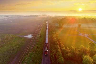 Freight train rolls through foggy rural landscape at sunrise