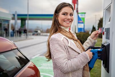 Portrait of young woman paying to charge her electric car