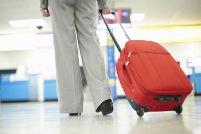 Young business woman walking with luggage towards check in gates in airport