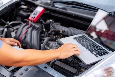 Mechanic man using laptop examining tuning fixing repairing car