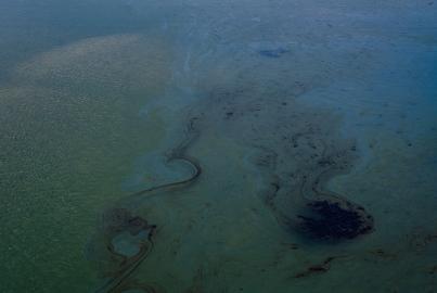 An oil patch floating in the water during an oil spill at a beach