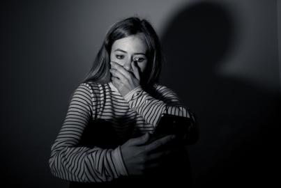 Sad desperate young teenager female girl on smart phone suffering from online bulling and harassment 