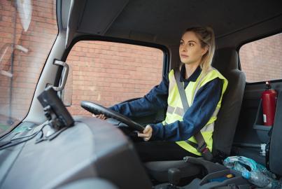 A close-up shot of a young female manual worker in a van driving to work