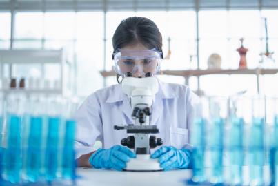 Labortechniker, der durch ein Mikroskop schaut, während er eine Genomprobe während der Forschung im Labor untersucht