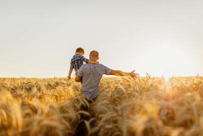 Père et fils s'amusant dans un champ agricole sur fond de ciel