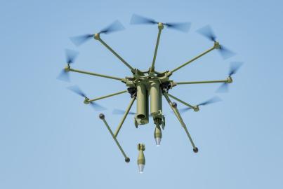 Military drone dropping bomb in blue sky