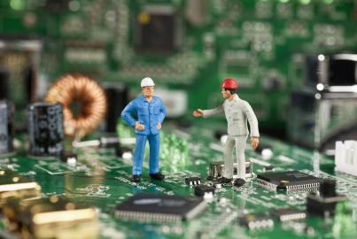 Deux figurines miniatures travaillant sur une carte mère d'ordinateur