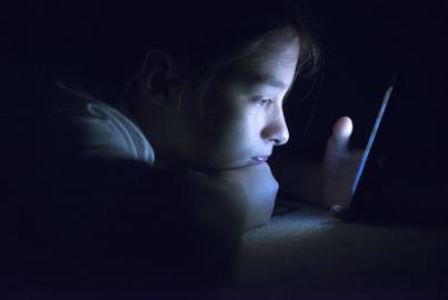 Teenager sending email from smart phone in her bed