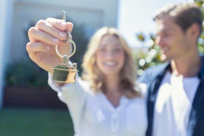 Young couple holding the key to their new house.