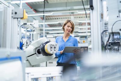 Businesswoman with tablet at assembly robot in a factory