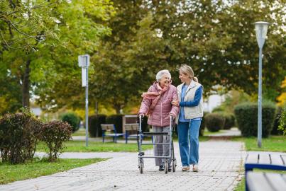 Senior woman and her home caregiver spending a chilly, windy day outdoors in city park.