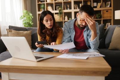 Couple feeling stress and frustration while analyzing financial documents at home